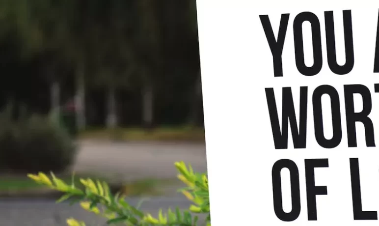 bord tekst buiten tegen een boom met tekst You are worthy of love