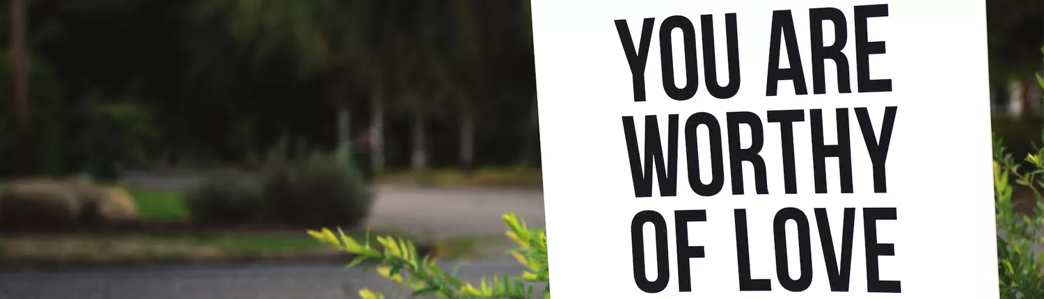 bord tekst buiten tegen een boom met tekst You are worthy of love