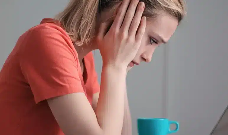 vrouw met handen in haar hoofd voor laptop