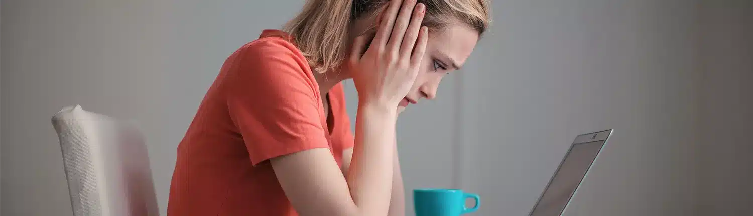 vrouw met handen in haar hoofd voor laptop