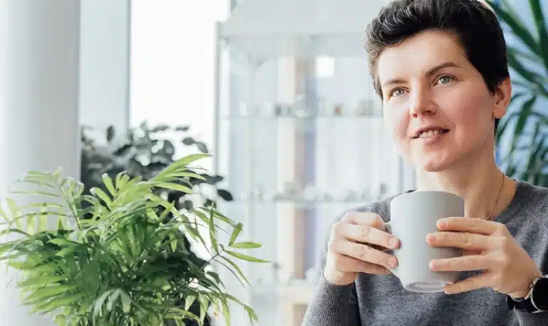 lachende vrouw met op de achtergrond een blauwe muur en 2 planten