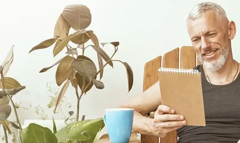 Man die een boek tussen zijn planten leest
