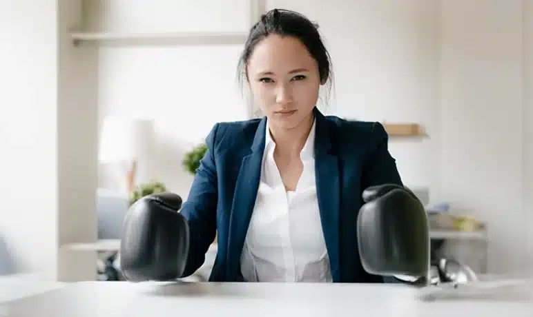 Vrouw die met bokshandschoenen aan haar bureau zit
