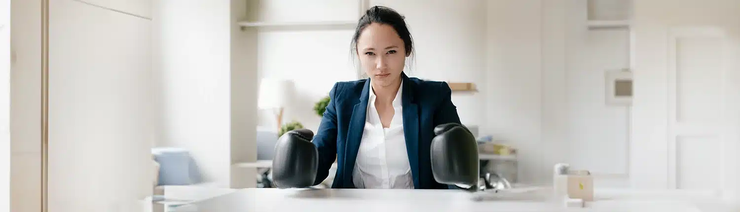 Vrouw die met bokshandschoenen aan haar bureau zit
